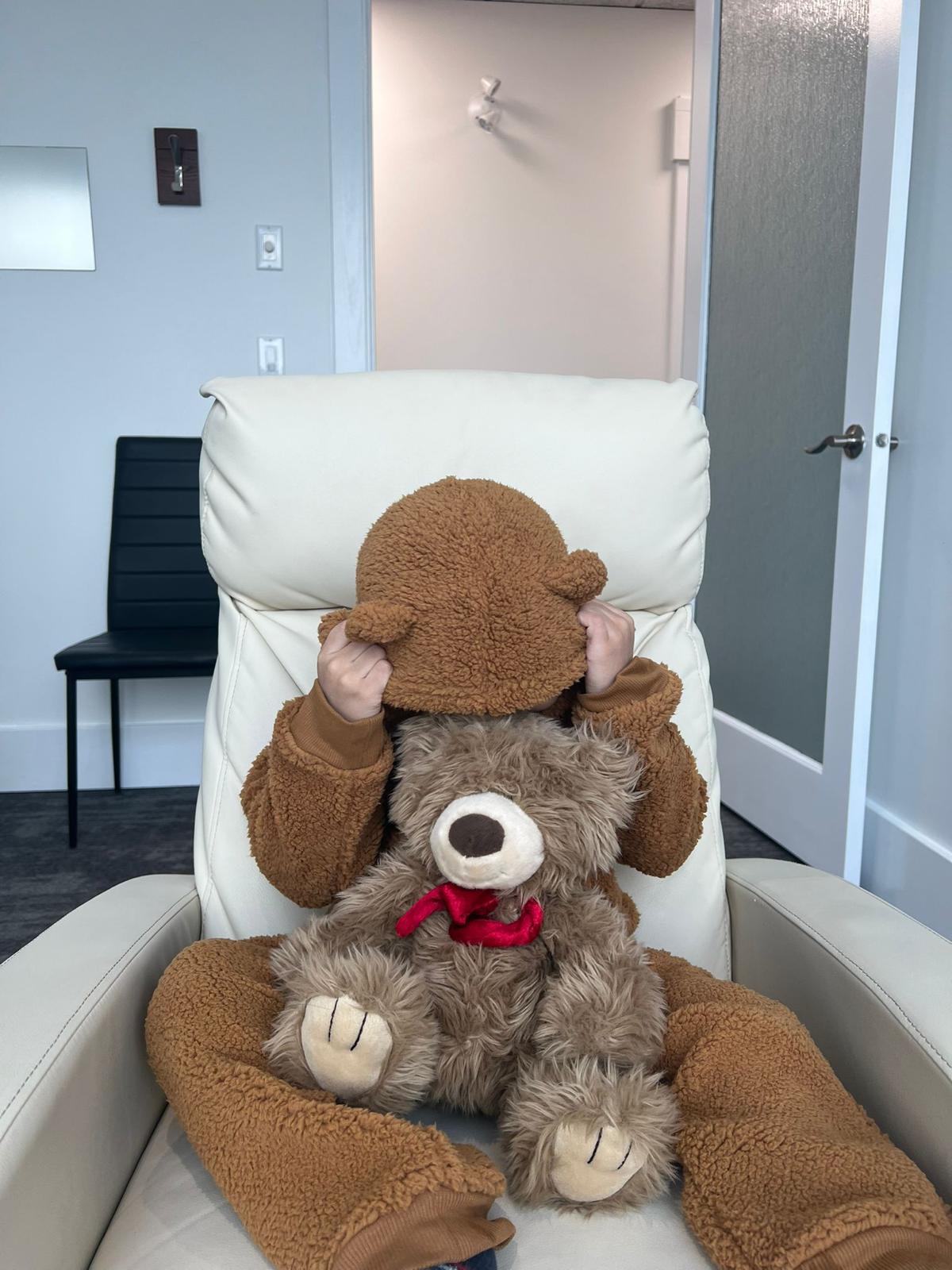 A child holding a teddy bear on the MeRT® treatment chair