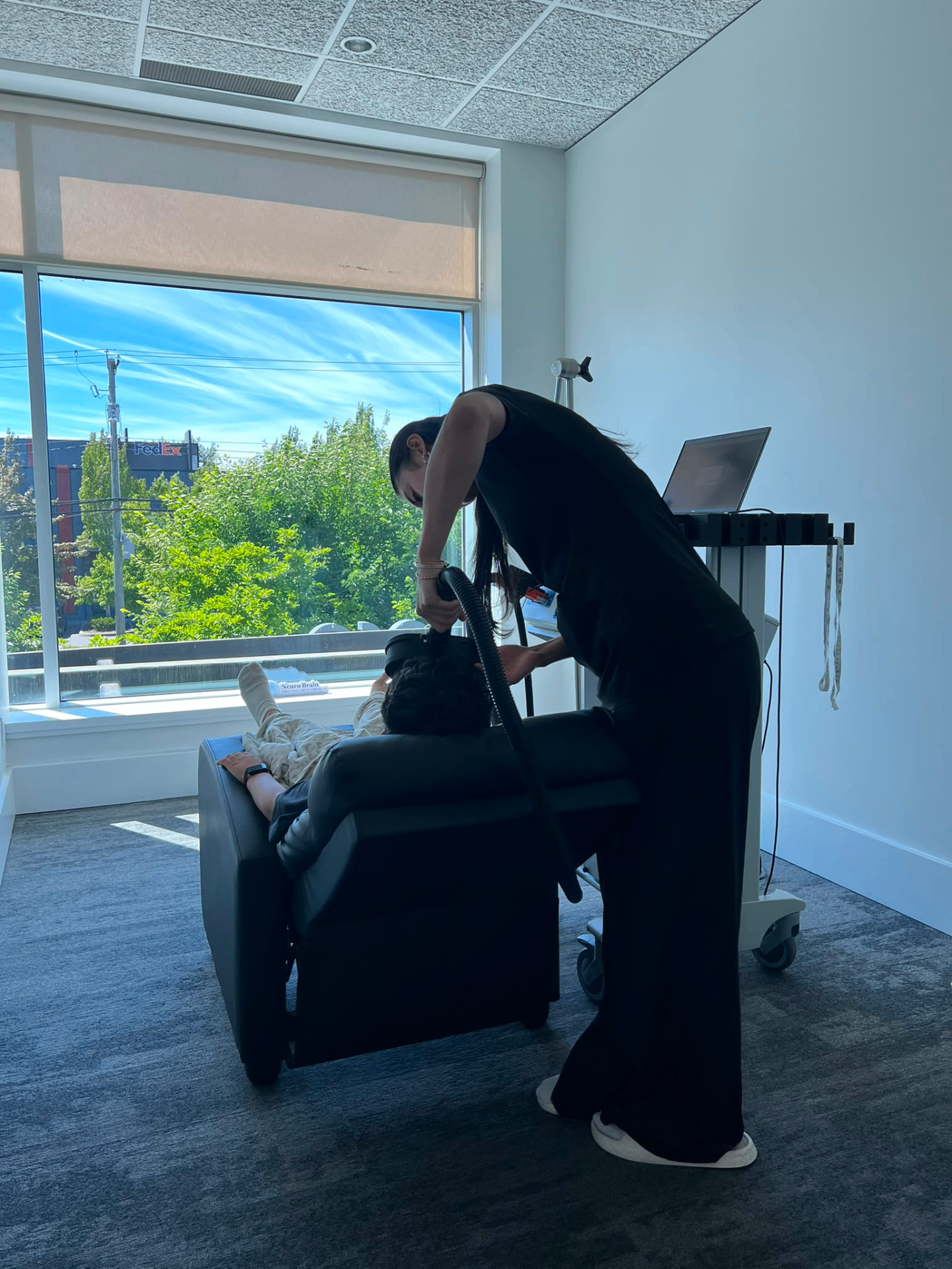 A clinician positioning the MeRT® coil for a patient reclined by the window